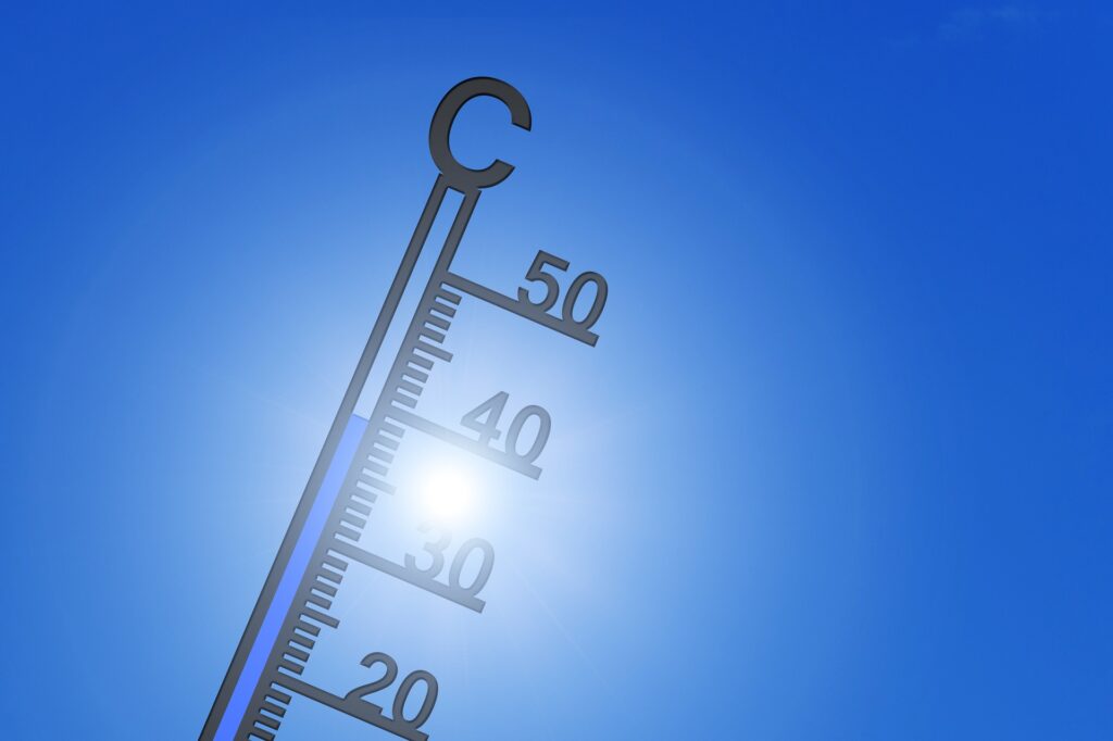 Thermometer with a sunny sky in the background, signalling heat